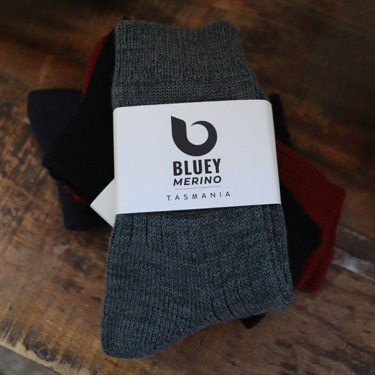 Pair of grey Tasmanian Merino socks with a Bluey Merino label on a wooden sheering table © Bluey Merino Tasmania
