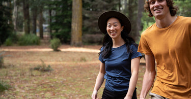 Two persons are happy walking in a beautiful forest. They are both wearing Bluey Merino t-shirts. 