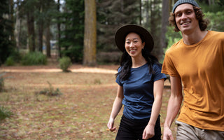 Two persons are happy walking in a beautiful forest. They are both wearing Bluey Merino t-shirts. 