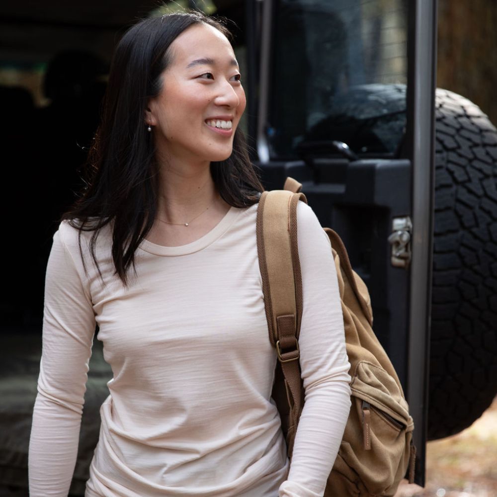 woman is standing in front of a 4WD Landrover Defender 110. She is wearing a base layer by © Bluey Merino Tasmania 