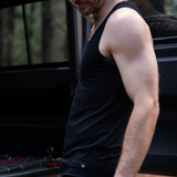 Steve is wearing the Men's Tasmanian Merino 150 Tank Top  in Currawong (black). He is standing next to the Land Rover 110 - Photography by Melanie Kate Creative -  © Bluey Merino