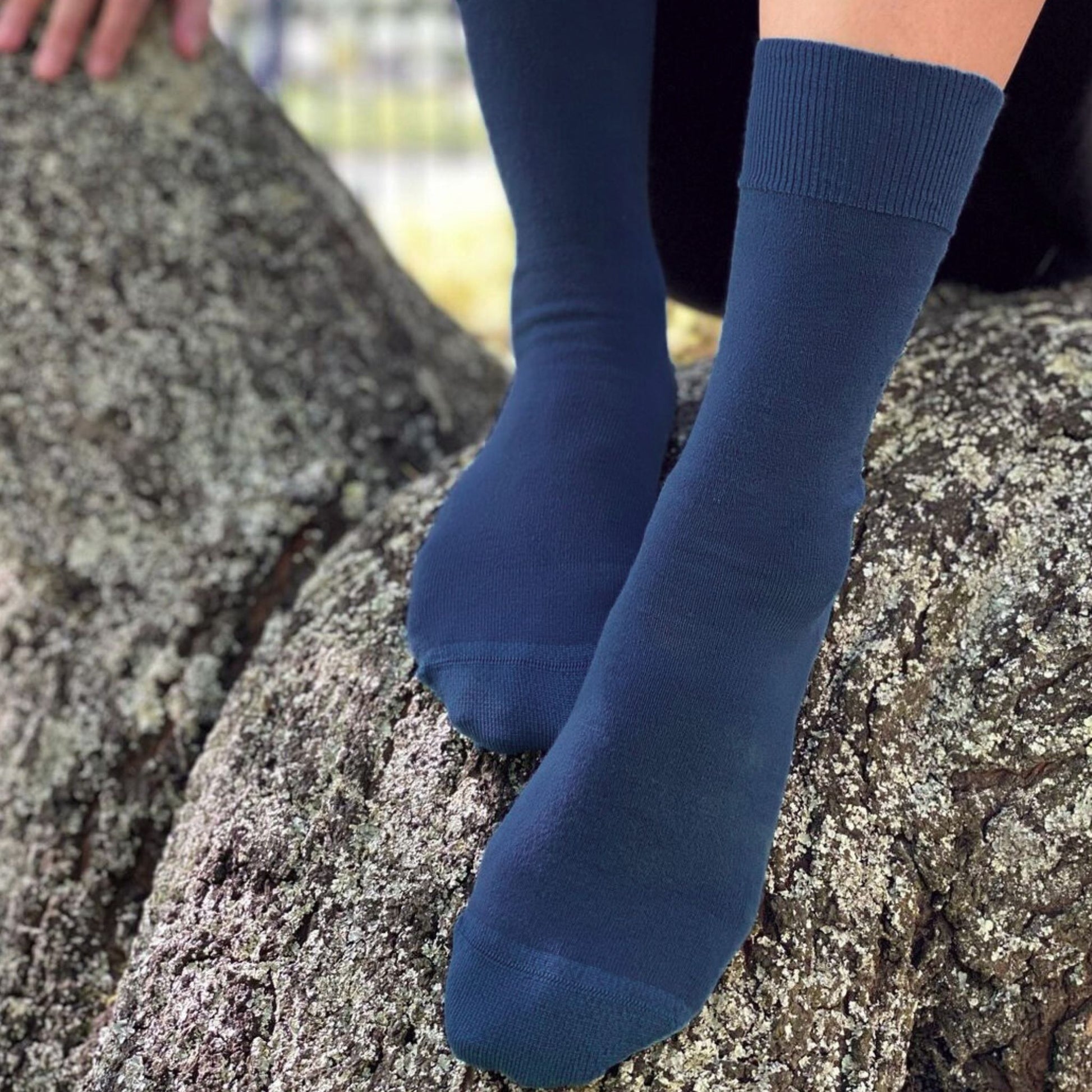 Person wearing blue socks sitting on a rock. Navy_Merino Wool Crew Sock. No itch guarantee. Health Sock. © Humphrey Law. Made in Australia.