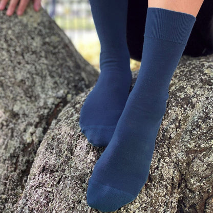Person wearing blue socks sitting on a rock. Navy_Merino Wool Crew Sock. No itch guarantee. Health Sock. © Humphrey Law. Made in Australia.