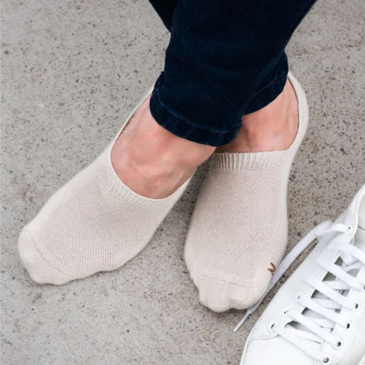 White sneakers with beige Merino no-show socks on a concrete surface © Humphrey law