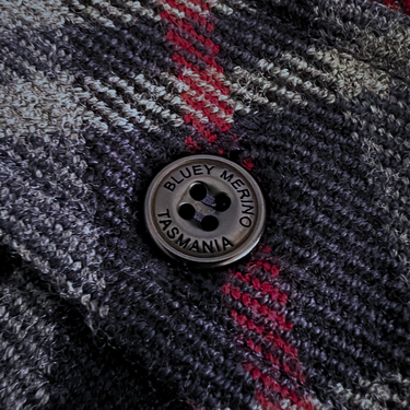 Close-up of a textured fabric with a button labeled 'Bluey Merino Tasmania'. Stanley Overshirt. Made in Tasmania.