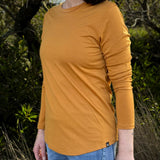 Person wearing a mustard yellow - Billy Button long-sleeve Merino shirt with a blurred natural background © Bluey Merino Tasmania
