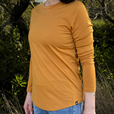 Person wearing a mustard yellow - Billy Button long-sleeve Merino shirt with a blurred natural background © Bluey Merino Tasmania