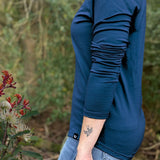 Person wearing a blue - Tasman Merino long-sleeve shirt with a blurred natural background @ Bluey Merino Tasmania
