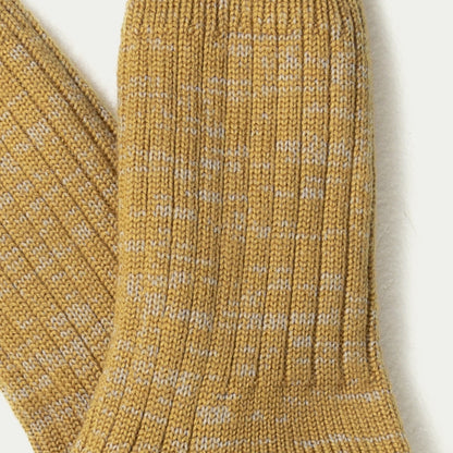 Close-up of a ribbed knit sock in a warm mustard yellow colour with subtle grey flecks throughout, shown against a plain light background. © Bluey Merino Tasmania