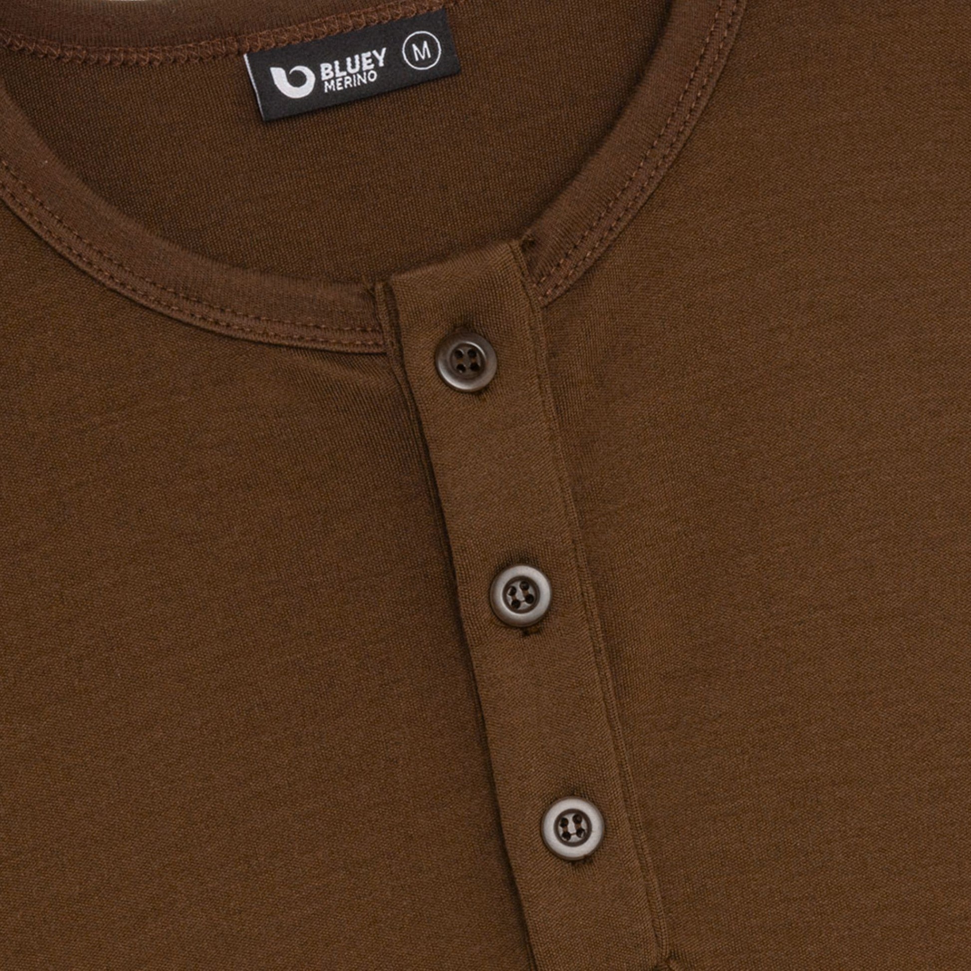 up close coconut buttons and neck. Merino Chestnut Brown long-sleeve henley shirt on a light grey background © Bluey Merino Tasmania