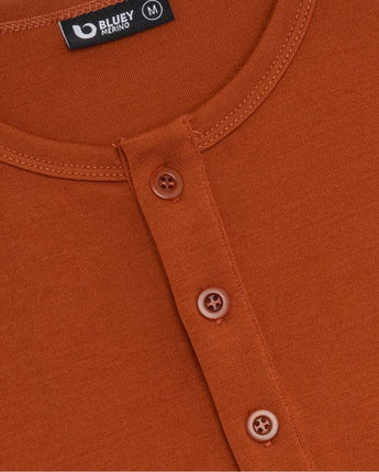 Close-up of an orange shirt with button details and a brand label.