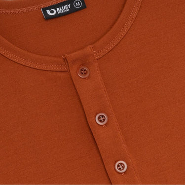 Close-up of an orange shirt with button details and a brand label.