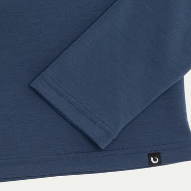 Close-up of a blue long-sleeve shirt with a brand logo on a white background