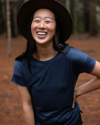 Happy women wearing a dark blue cropped Merino t-shirt and hat in a northern Tasmanian forest setting. © Bluey Merino Tasmania