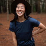Happy women wearing a dark blue cropped Merino t-shirt and hat in a northern Tasmanian forest setting. © Bluey Merino Tasmania