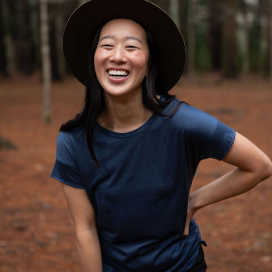 Happy women wearing a dark blue cropped Merino t-shirt and hat in a northern Tasmanian forest setting. © Bluey Merino Tasmania