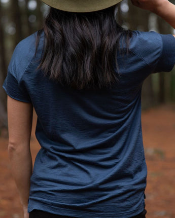 Person seen from the back, wearing a dark blue cropped Merino t-shirt and hat in a northern Tasmanian forest setting. © Bluey Merino Tasmania