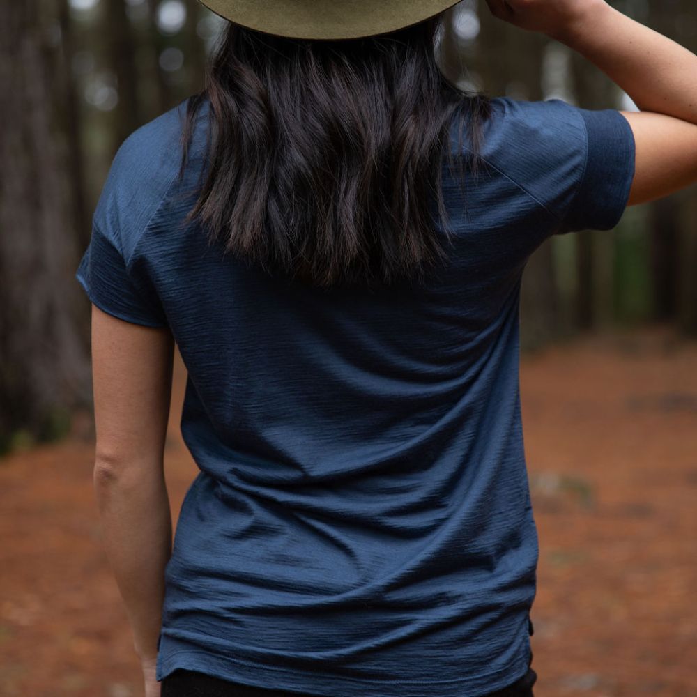 Person seen from the back, wearing a dark blue cropped Merino t-shirt and hat in a northern Tasmanian forest setting. © Bluey Merino Tasmania