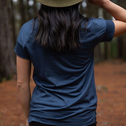 Person seen from the back, wearing a dark blue cropped Merino t-shirt and hat in a northern Tasmanian forest setting. © Bluey Merino Tasmania