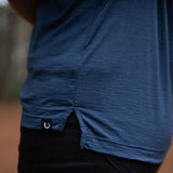 Close-up of the fit and tag of a person wearing a french navy blue Merino shirt with a blurred background and black jeans © Bluey Merino Tasmania