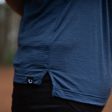 Close-up of the fit and tag of a person wearing a french navy blue Merino shirt with a blurred background and black jeans © Bluey Merino Tasmania