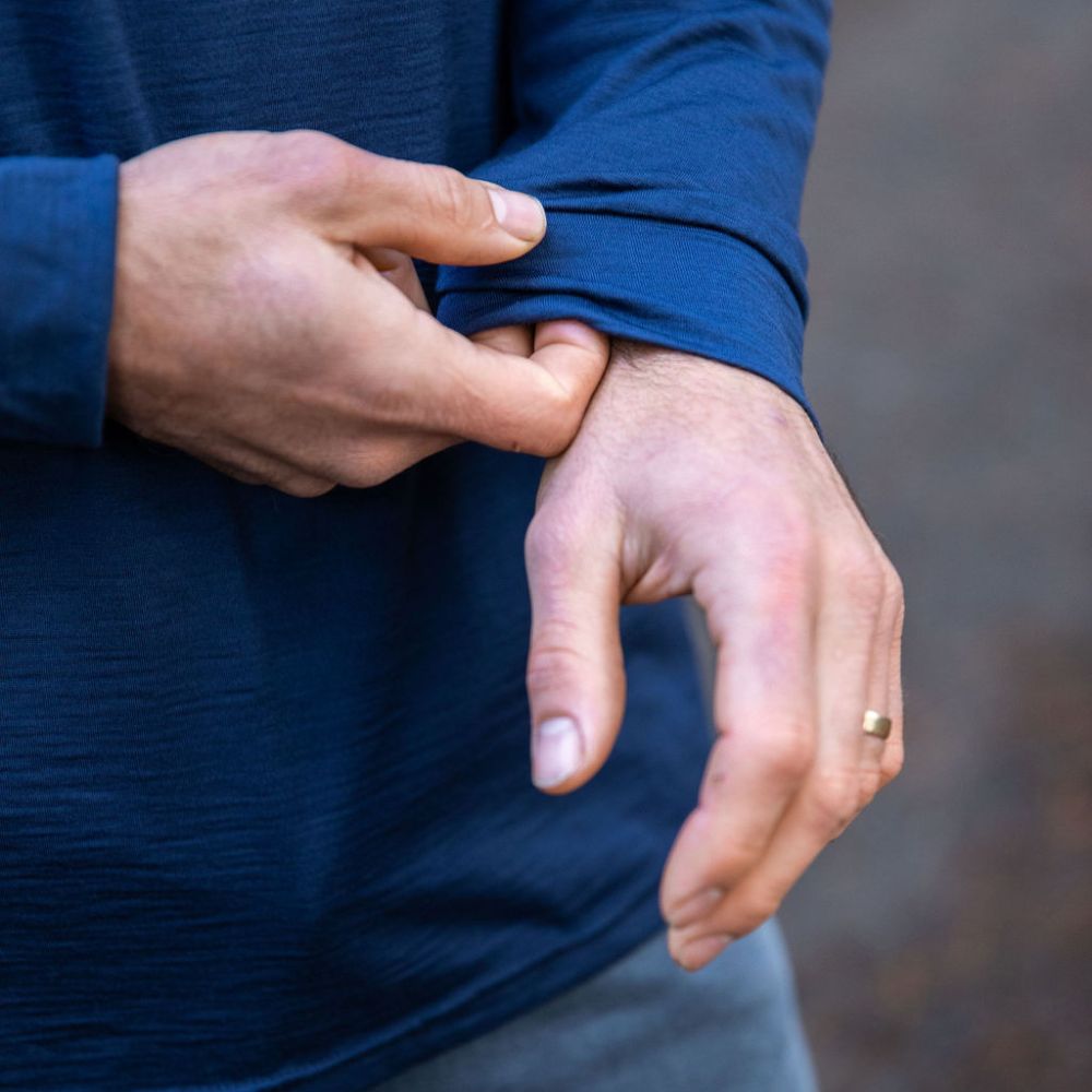 Person adjusting the sleeve of a Merino blue long-sleeve shirt against a blurred background © Bluey Merino Tasmania
