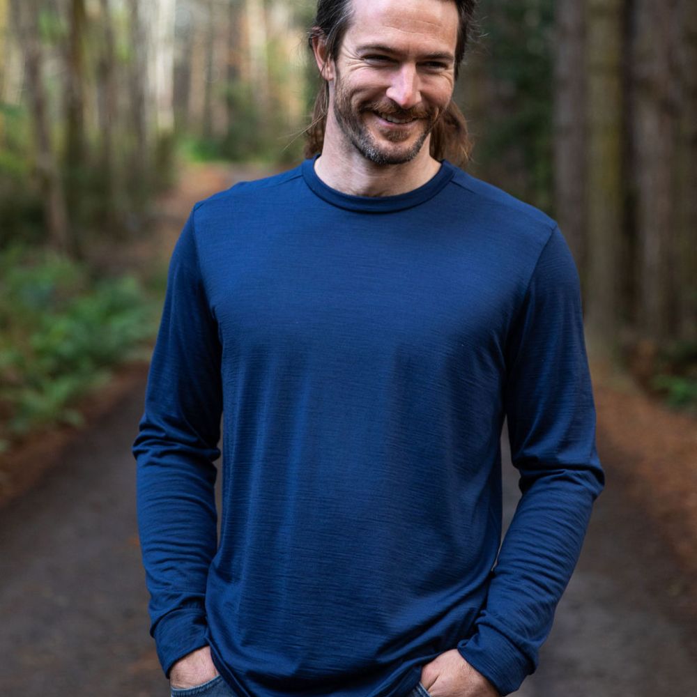 Man wearing a blue long-sleeve Merino shirt standing in a forest. Image © Bluey Merino Tasmania