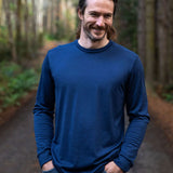 Man wearing a blue long-sleeve Merino shirt standing in a forest. Image © Bluey Merino Tasmania