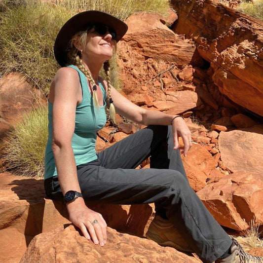 Woman wearing Bluey Merino tank top sitting on a rock in a desert landscape in the Australian outback © Amanda Westwood