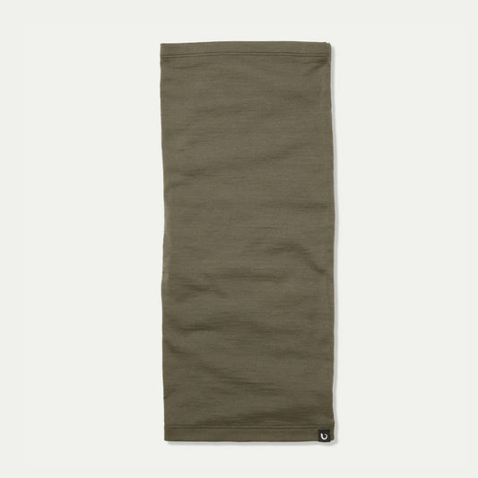 An light sage green Merino neck gaiter laid flat against a light off-white background, featuring a small black Bluey Merino logo patch on the bottom right hem. © Bluey Merino Tasmania