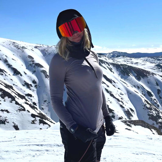 Person in winter gear with goggles standing on a snowy mountain in NSW Australia wearing the 160 Everyday Merino base layer in the colour dusk © Alex Parsons