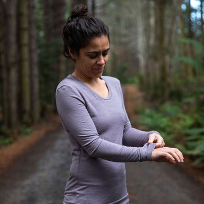 Woman standing in northern Tasmania wilderness wearing the 160 Merino Hike in the colour dusk. She is feeling the softness of the fabric with her hand © Bluey Merino Tasmania