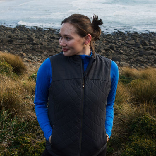Woman wearing a Merino gilet standing on a rocky coastal landscape in northern Tasmania © Bluey Merino Tasmania