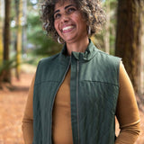 Smiling woman wearing an olive green Merino quilted gilet vest in a forest in northern Tasmania © Bluey Merino Tasmania