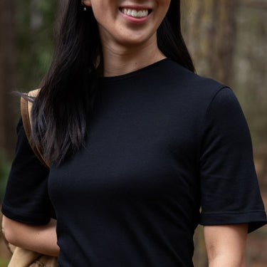 Person wearing a black t-shirt with a blurred natural background in northern Tasmania © Bluey Merino Tasmania