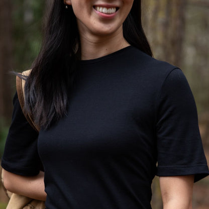 Person wearing a black t-shirt with a blurred natural background in northern Tasmania © Bluey Merino Tasmania