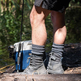 Person wearing hiking boots and socks standing on a log with a cooler and fishing rod in the background. XHF_Thermal Wool Sock. © Humphrey Law. Made in Australia.