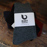 Pair of grey Tasmanian Merino socks with a Bluey Merino label on a wooden tray © Bluey Merino Tasmania