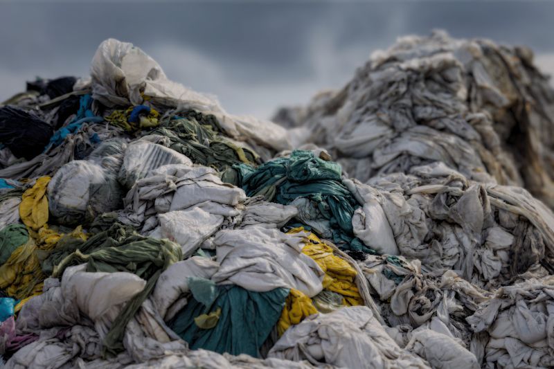 Discarded textile pollution - clothes pilled up. Dirty and unwanted. awful waste.